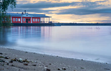 Smooth lake on a calm summer evening with a pier in the background and a beautiful sunset skyの写真素材