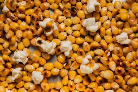 popcorn grains in oil and salt, stainless pan bottom, with some burst beansの写真素材