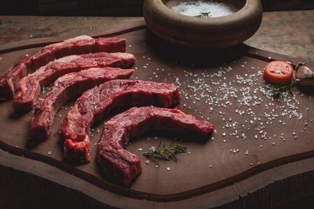 raw beef ribs in small pieces, with salt and green seasoning, on textured wooden backgroundの写真素材