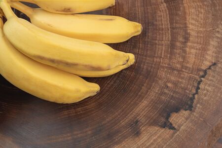 close up bunch of bananas with wooden trunk background, normal appearance, natural light and space for writingの写真素材