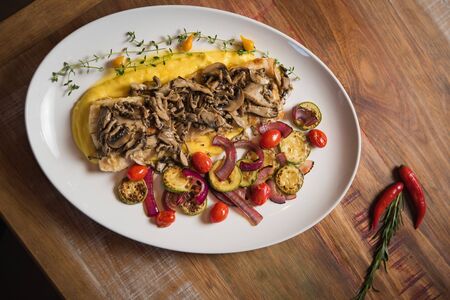 Grilled fish with mushrooms on â butter, accompanied by â potato, tomato â sweetgrape, red onion and zucchini confit â の写真素材