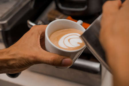 Close-up image of barista putting tamper in coffee machine when brewing drink for customerの写真素材