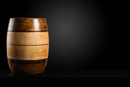 Two-color wooden barrel on black table and dark background, copy spaceの写真素材