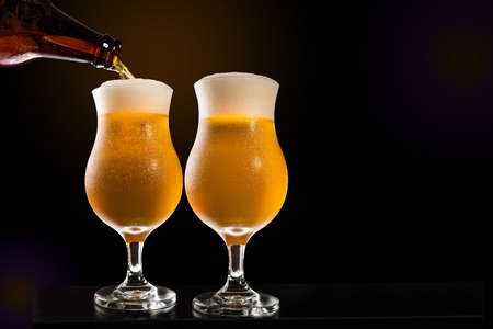 Glass being filled with a beer from the bootle, with white background, in a concept of celebration or contemplation of the process.の写真素材
