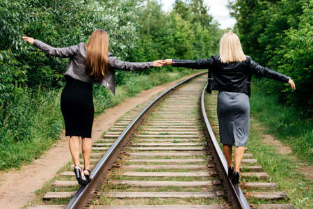 Girls go by rail holding hands in summerの写真素材
