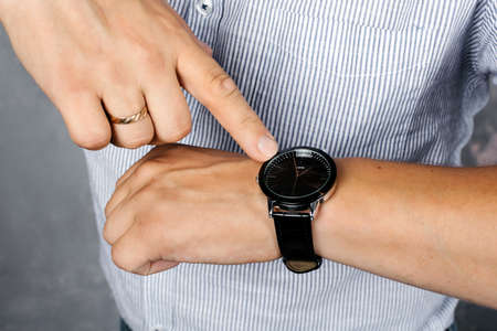 A man in a shirt points to a wristwatch