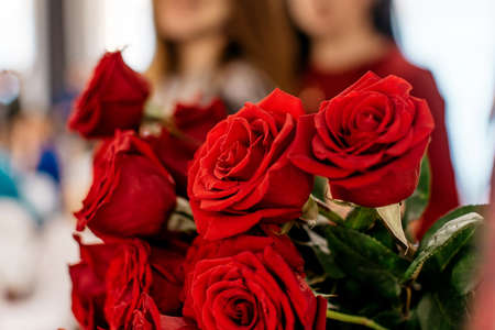 Bouquet of red roses with girls in the backgroundの写真素材