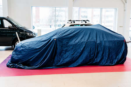Car in a car dealership under a blue blanket