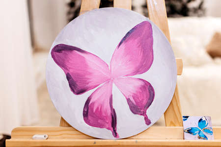 Painting of a purple butterfly with watercolor paints on a round backgroundの写真素材
