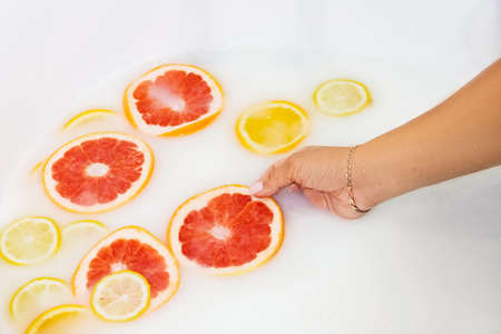 Lots of red and yellow citruses in milk close upの写真素材