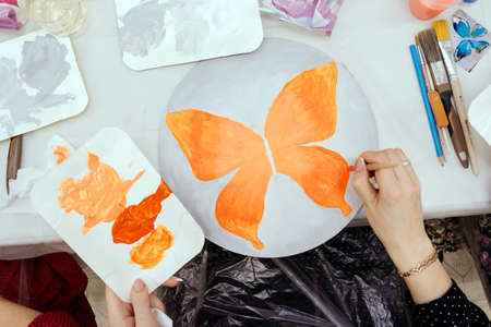 Girl painting an orange butterfly with watercolors