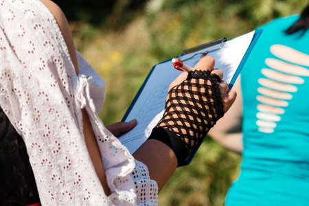 Woman in a suit writes in a notebook on nature close upの写真素材