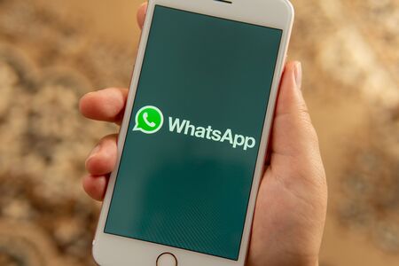 Palo Alto / USA - August 08 2019: Female hand with Apple phone with logo of social media WhatsApp on the screen. Social media icon. Can be used as illustration for news media or marketing conceptのeditorial素材