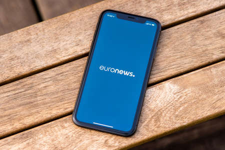 Tallinn / Estonia - September 28, 2020: Black iphone with logo of news media EuroNews on the screen. Wooden background. Can be used as illustrative for marketing or business conceptのeditorial素材