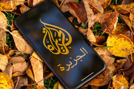 Tallinn / Estonia - September 28, 2020: Black iphone with logo of news media Al Jazeera on the screen. Falled leaves background. Can be used as illustrative for marketing or business conceptのeditorial素材