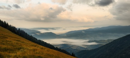 Panoramic sunrise mountains landscape with foggy valleys and forests and pink cloudsの写真素材