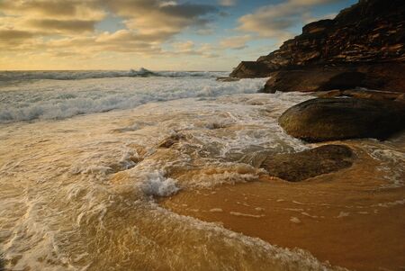Moody sunrise seascape with colored clouds and flowing waterの写真素材