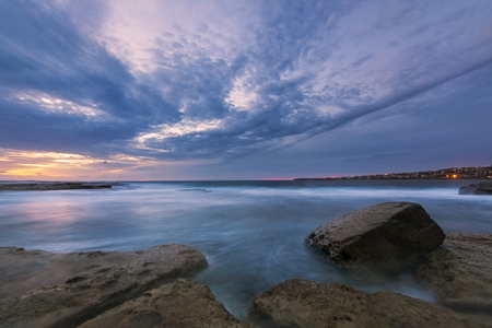 Long exposure seascape dawn with distant city lights before sunriseの写真素材