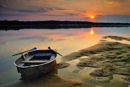 Sunrise on the river with a sand moored boat and calm mirror water surfaceの写真素材