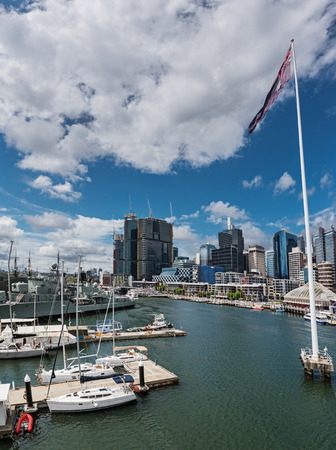 Darling harbor during the day with cruising ships and boats and sydney skyline and australian flagの写真素材