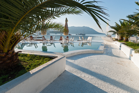 Closed cafeafter sunrise on the beach in Budva, Montenegro with large umbrellas, round tables and chaird near the poolのeditorial素材
