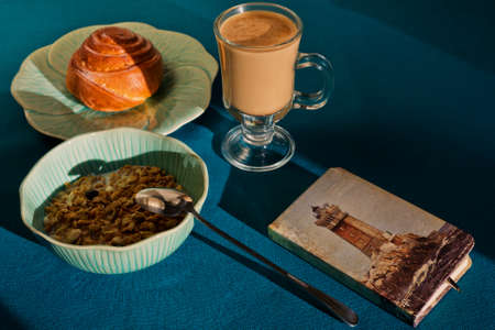 Breakfast with cinnamon bun, muesli and coffee in flower-like plate and bowl