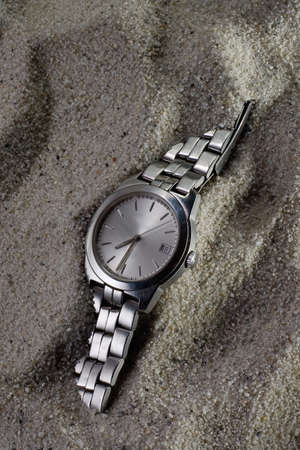 Old scratched watch, hand clock covered by sand, lost in time, their time has passed, allegory for the past timesの写真素材