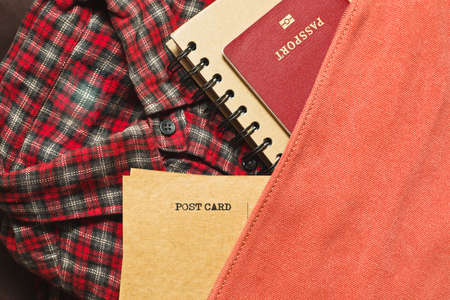 Some belongings prepared for travel: checkered cowboy styled shirt, passport, postcards, notebookの写真素材