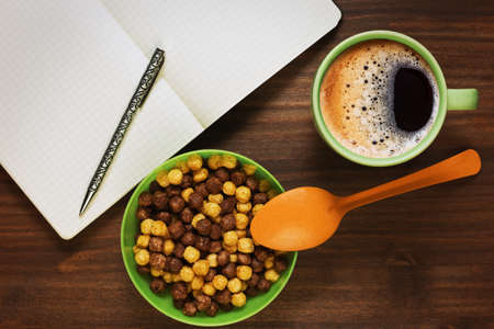 Planning the day or educating while having healthy breakfast of two varieties corn cereals and fresh...