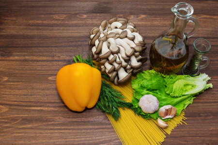 Everything is ready for pasta cooking on the table - spaghetti, olove oil with herbs, mushrooms, bell pepper, spices and herbs and so onの写真素材
