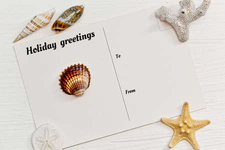 Blank postcard with vacations tagline and some sea shells on the rude wooden surfaceの写真素材