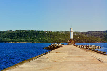 Navigation lighthouse in the end of the old pier with light leakの写真素材