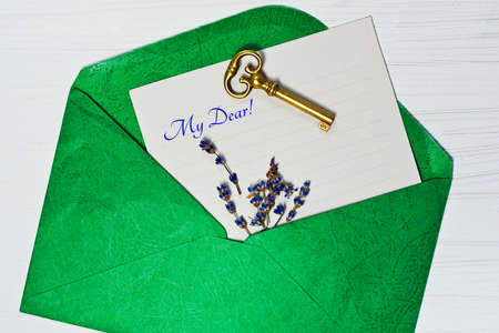Romantic message concept - green crafted envelope with copper key and dried lavender flowers in top viewの写真素材