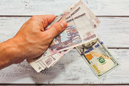MOSCOW, RUSSIA - JULY 26, 2017: Person is giving a lot of russian money for exchange to one hundred US dollars because of high exchange courseのeditorial素材