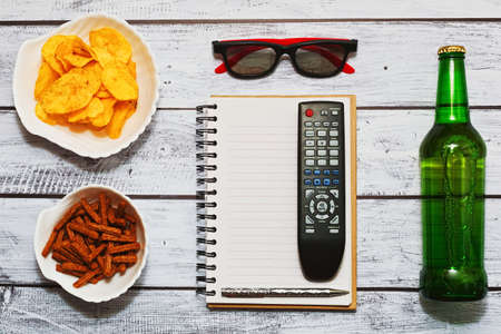 Relaxing watching sports by TV with a bottle of beer and snacks concept - top view, flat layの写真素材