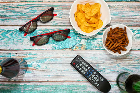 Home party for couple flatlay concept - beer, salted snacks. remote control and TV glasses on grungy table in top viewの写真素材