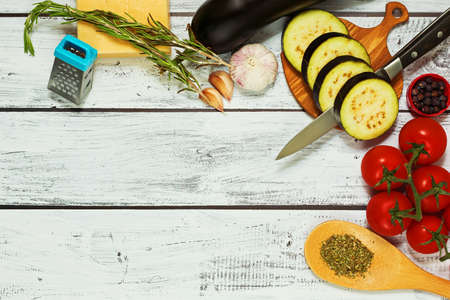 Kitchen background in rural style - eggplants, tomatoes, garlic, rosemary, black pepper, cheese....