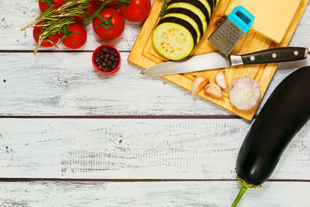 Ingredients for making grilled eggplants - raw eggpplants, fresh tomatoes, organic herbs, hard cheese, garlic and pepper. Top view in rustic rural style.の写真素材