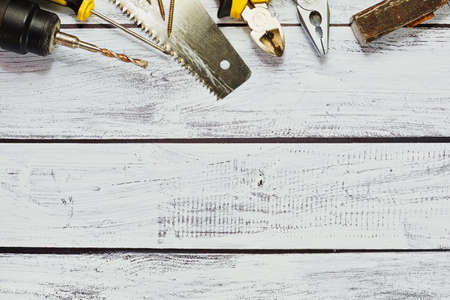 Some hand tools - saw, drilling machine, hammer, pliers, nippers and screwdrivers - on the wooden background with rough texture. Flay lay, top view.の写真素材