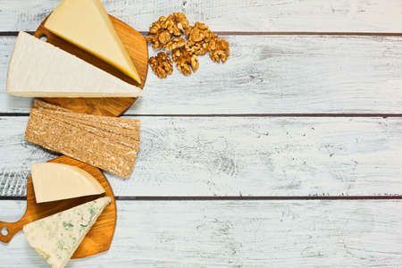 Different gourmet cheeses such as brie, camembert, parmesan - soft and hard, with white and blue mold - with walnuts and crispy rye bread. Top view on rural style wooden table. Place for text.の写真素材