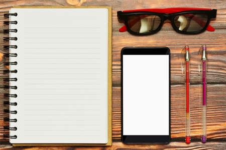 Office working place concept with blank notepad and smartphone with empty screen - copyspaces for text ot design, usable as a mockup.  Different office accessories lei nearby. Top view, flat lay.の写真素材