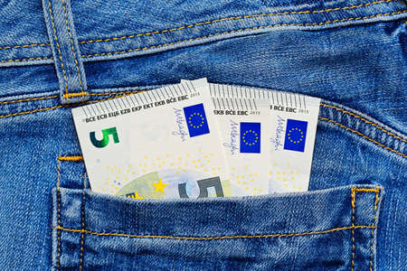 Small amount - three 5 euro banknotes in blue jeans pocket. Spending pocket money or financial...