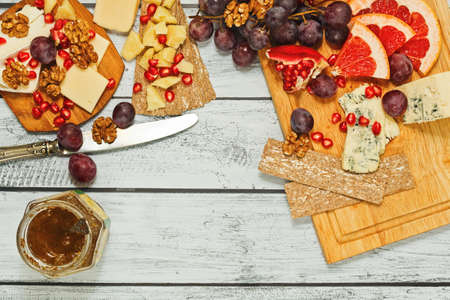 Snack board in european style - gourmet aged ripe cheese of different varieties - camembert, roquefort, parmesan, cheddar - with different fruits, nuts, crackers and jam. Top view.の写真素材