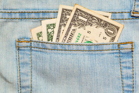 Few one US dollar banknotes in worn blue jeans pocket - allowance. Alms or pocket money concept,...