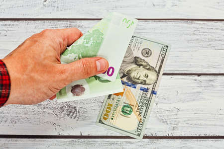 Male person with rough skin wearing checkered classic shirt changing 50 euro banknote to 100 US dollars. European financial crisis and the fall of the euro exchange rate concept.の写真素材