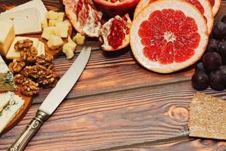 Healthy and tasty ready to eat snack - refined gourmet cheese, fresh fruits and walnuts with rye crackers. Perfect lunch idea or wine appetizer set. Close-up capture, selective focus.の写真素材