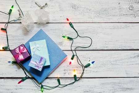 Christmas and New Year gifts in boxes and traditional home decorations - angel figurines and multicolor garland - on the wooden loft style background. High angle view, place for text.の写真素材