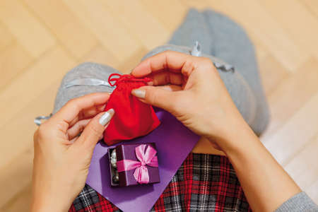 Person in schoolgirl checkered skirt and high warmer socks with some little gifts presented on holiday probably Saint Valentine day and a congratulation card on her knees. First person top view.の写真素材