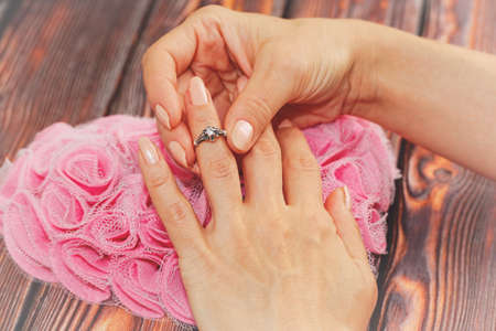 Young adult female person puts on a silver ring with a jewel. Heart shaped decoration on the...