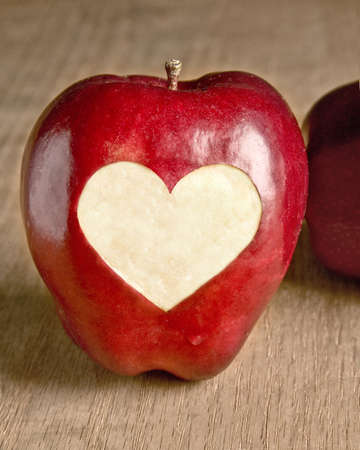 Heart cut into an apple on a wooden background